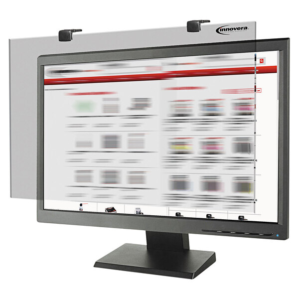 A white Innovera premium antiglare privacy monitor filter on a computer screen with a blurry image of a newspaper.