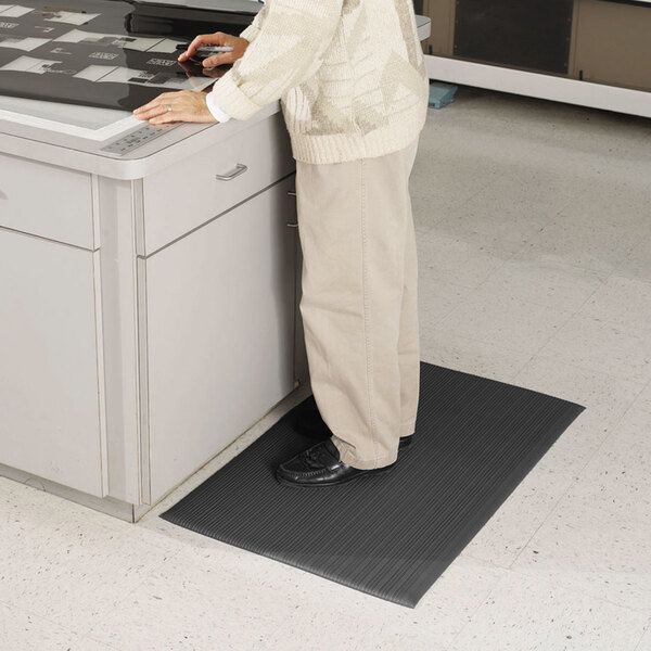 A person standing on a black Guardian Air Step anti-fatigue floor mat.