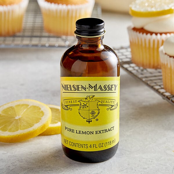 A bottle of Nielsen-Massey Pure Lemon Extract next to a lemon cupcake.