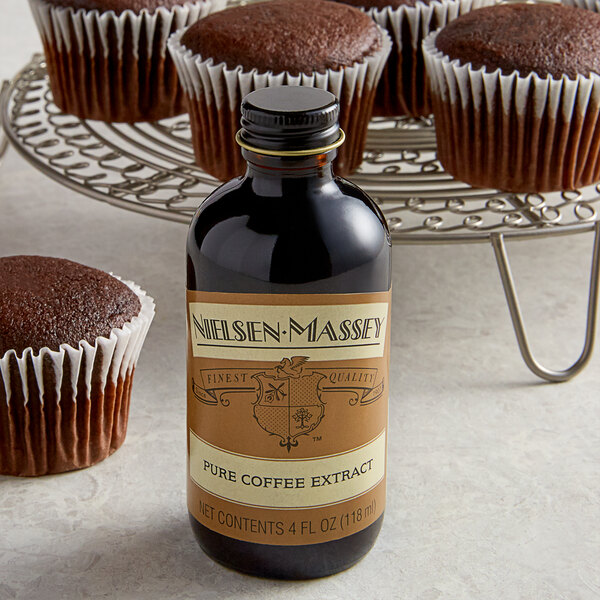 A bottle of Nielsen-Massey Pure Coffee Extract next to chocolate cupcakes.