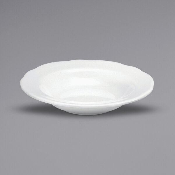 A white bowl with scalloped edges on a gray surface.