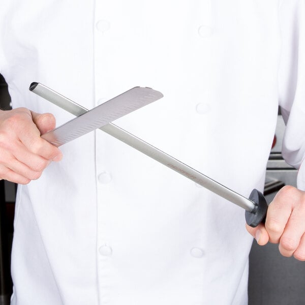 A chef using a Dexter-Russell oval knife sharpening steel on a white knife.