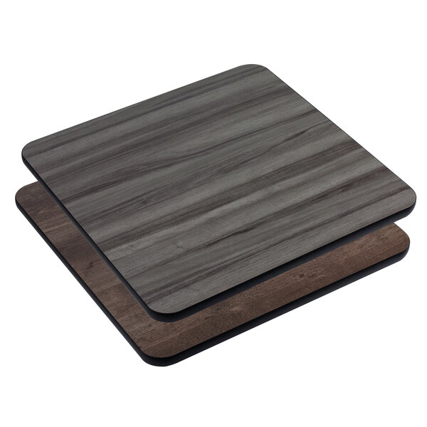 Two American Tables & Seating square wood table tops with gray and brown laminate panels stacked on top.