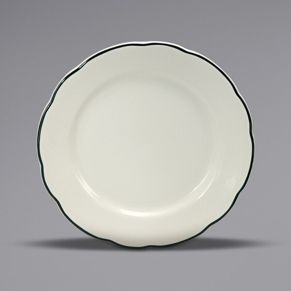 A white plate with a scalloped edge and black trim.