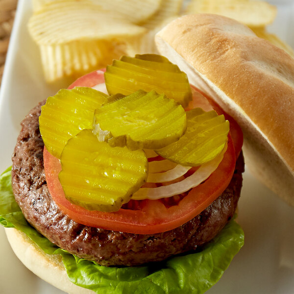 A hamburger with Del Sol dill pickle chips on a plate.