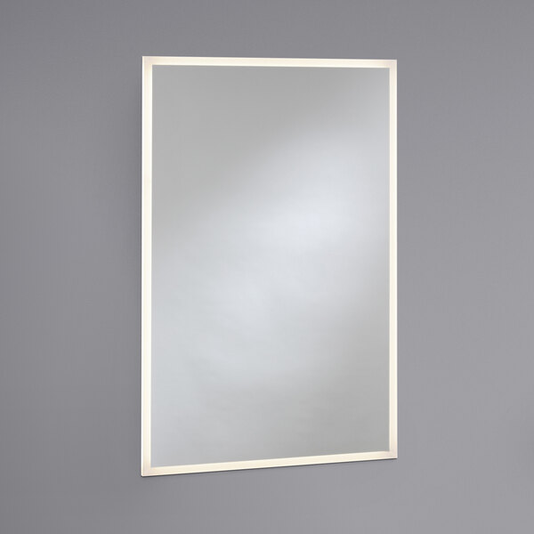 A Bobrick LED backlit rectangular mirror with a white border on a wall.