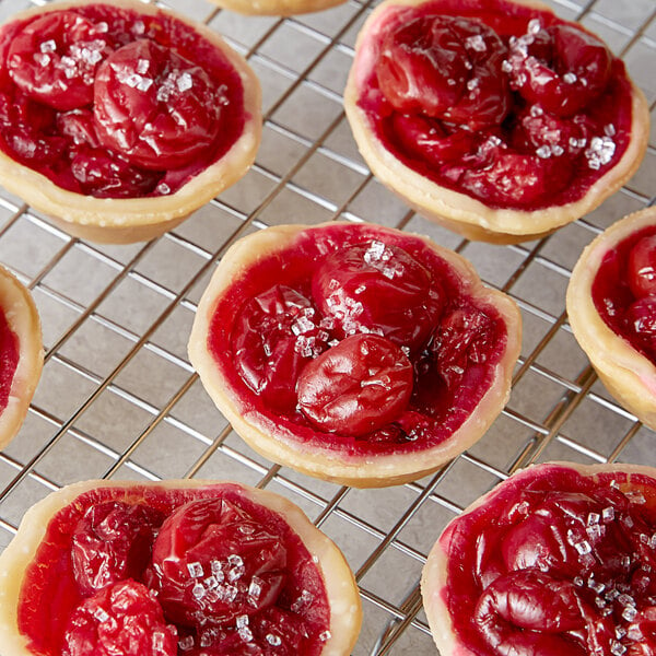 A group of small cherry pies on a cooling rack.
