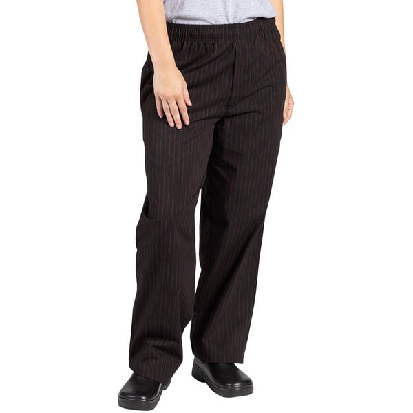 A woman wearing Uncommon Chef black chef pants with red pinstripes.