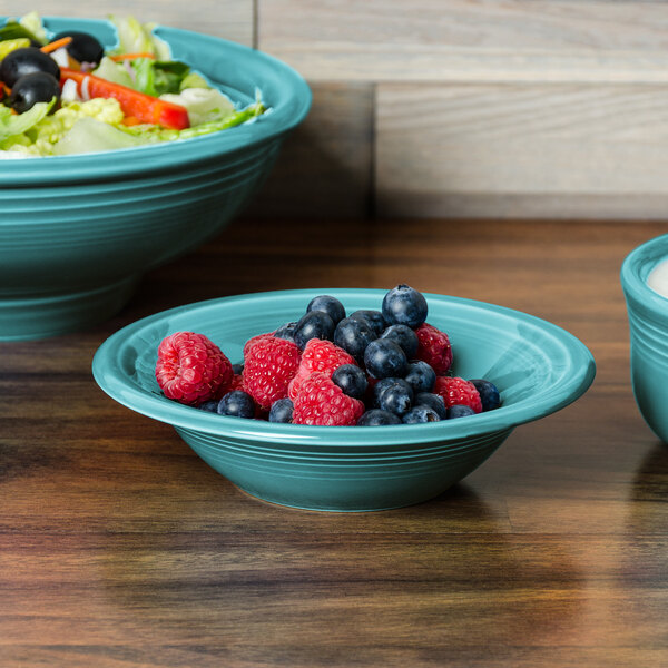 A turquoise Fiesta china bowl filled with blueberries and raspberries.
