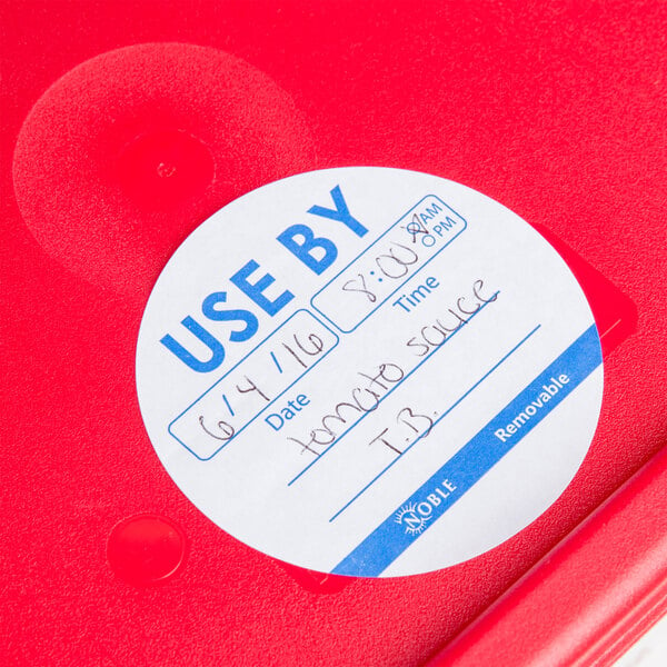 A red plastic container with a white Noble Products round "Use By" label.