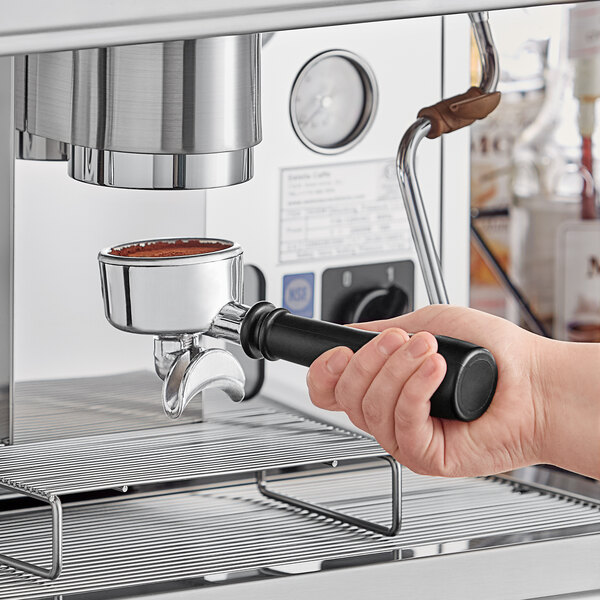 A person holding an Estella Caffe two group automatic espresso machine over a counter.