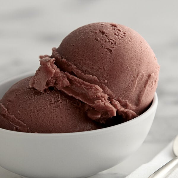 A bowl of black cherry Italian ice with a spoon.