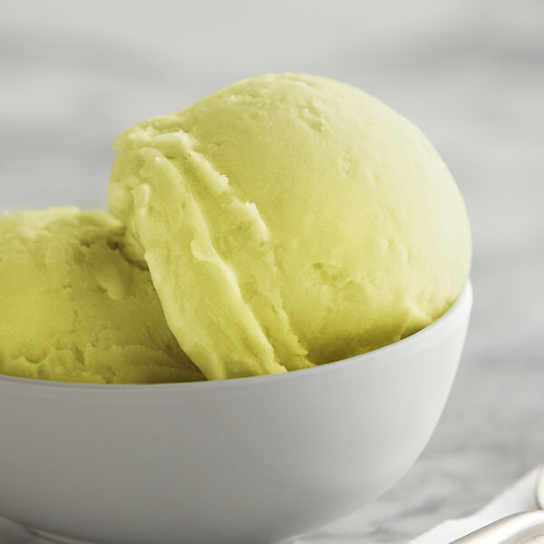 A bowl of pineapple Italian ice with a scoop of pineapple Italian ice.