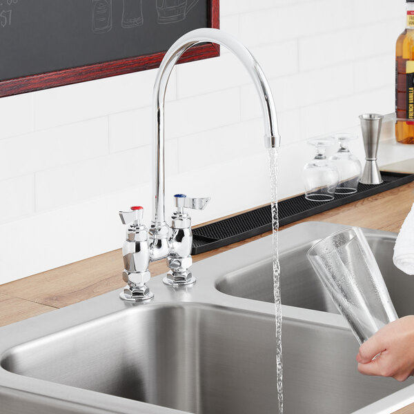 A woman using a Waterloo gooseneck faucet to pour water into a glass over a sink.