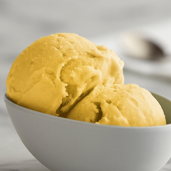 A bowl of I. Rice Mango Italian Ice with a scoop of yellow and white swirls.