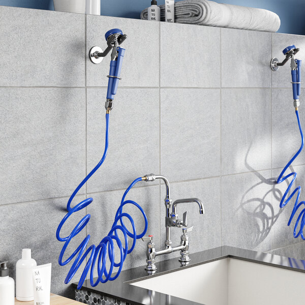 A wall-mounted faucet with a 6-inch swing spout and a blue coiled hose attachment above a utility sink.