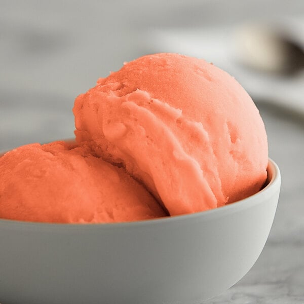 A bowl of I. Rice strawberry lemonade ice base with a scoop of orange Italian ice.