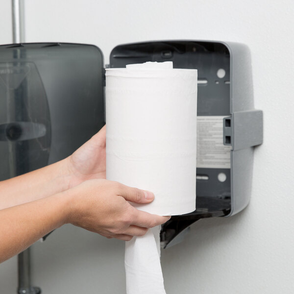 A person's hands holding a Lavex Junior Center Pull Paper Towel roll.