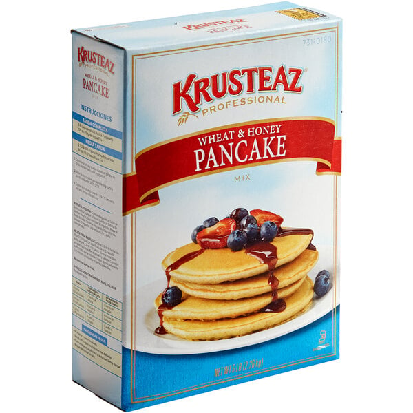 A box of Krusteaz Wheat & Honey Pancake Mix with a stack of pancakes with syrup.