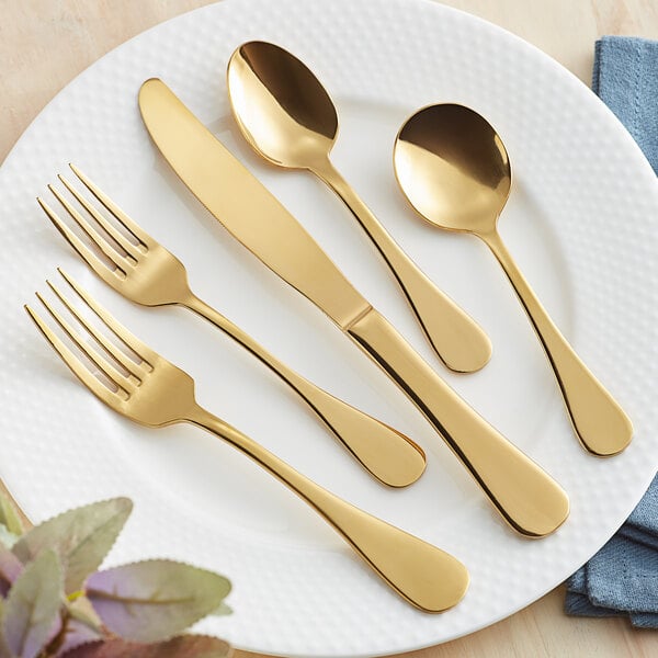 A white plate with Acopa Vernon gold flatware including a fork and spoon.