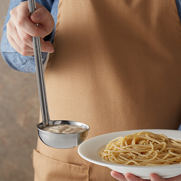 A person using a Vollrath stainless steel ladle to serve spaghetti.