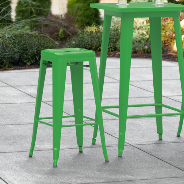 A Lancaster Table & Seating green outdoor bar stool on a patio.