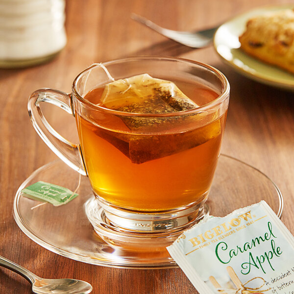 A glass cup of Bigelow Caramel Apple Tea with a tea bag in it.