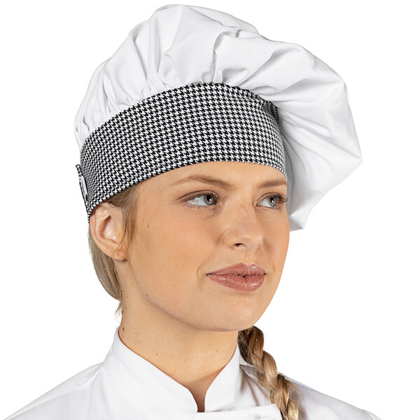 A woman wearing a white twill chef hat with a houndstooth band.