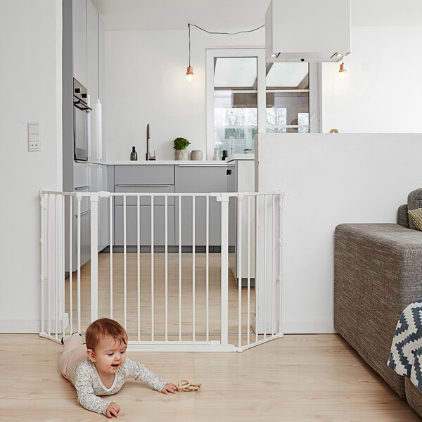 A baby crawling in front of a white L.A. Baby safety gate.