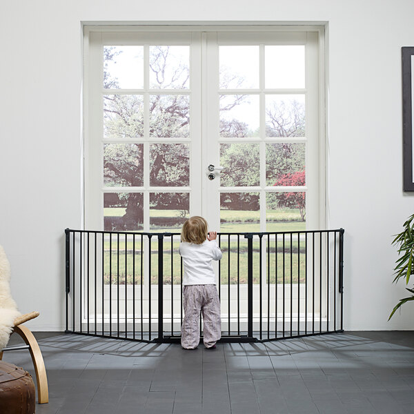 A child standing in front of a black BabyDan safety gate.