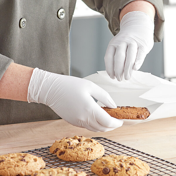 A person wearing Noble Products Nitrile gloves holds a cookie.