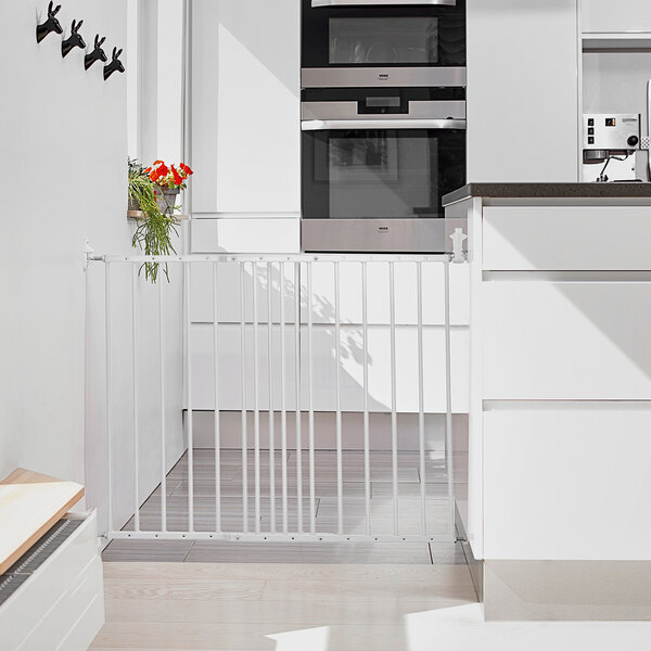 A kitchen with a white L.A. Baby BabyDan extending safety gate over an oven.