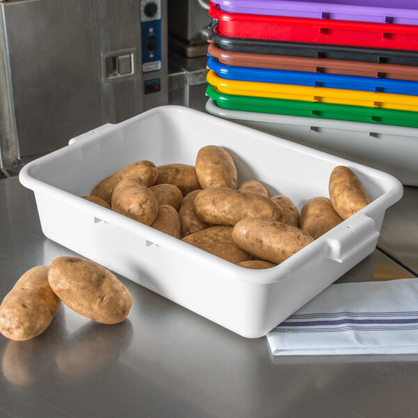 A white Carlisle food storage box filled with brown potatoes.