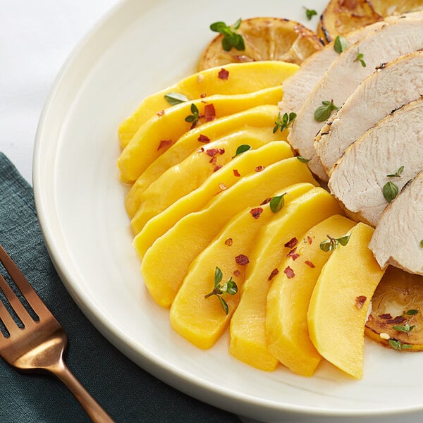 A plate of food with sliced Dole mangoes and chicken.