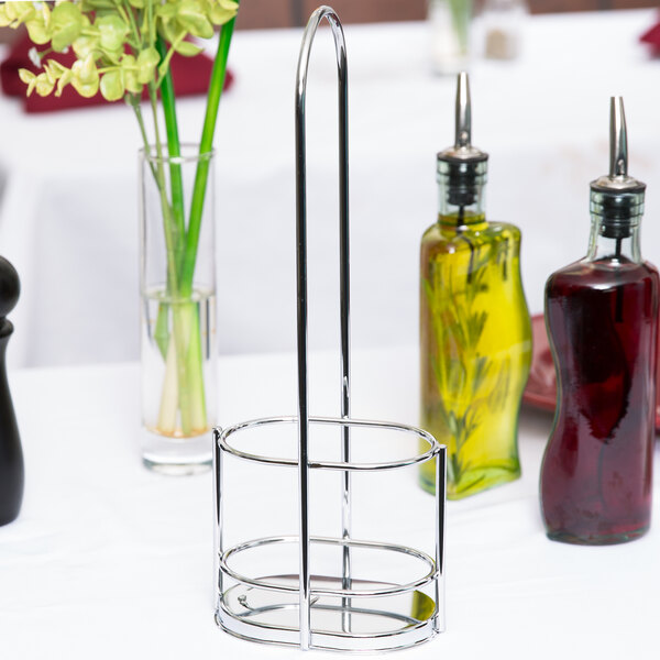 A Tablecraft chrome metal rack holding olive oil cruets and flowers on a table.