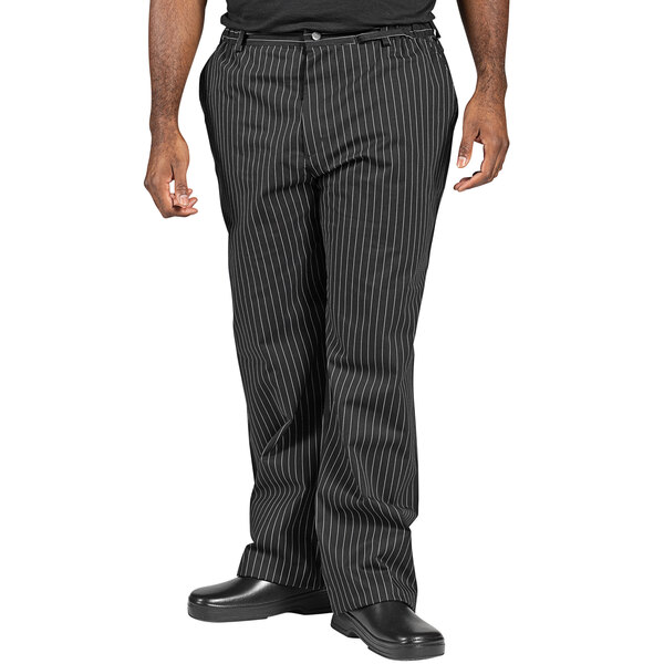 A man wearing black and white pinstripe chef pants.