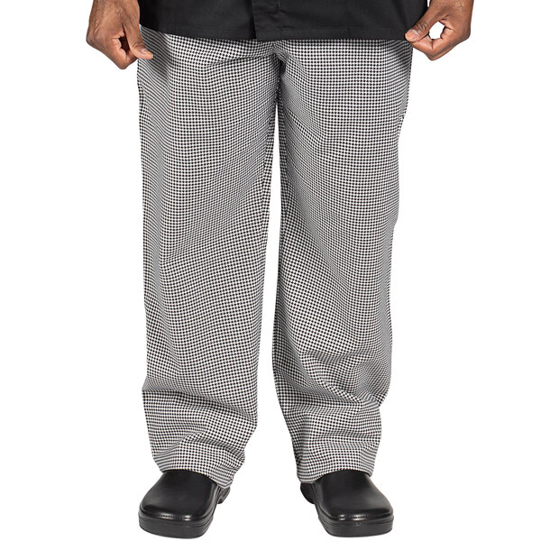 A man wearing Uncommon Chef Houndstooth executive chef pants with a checkered pattern.