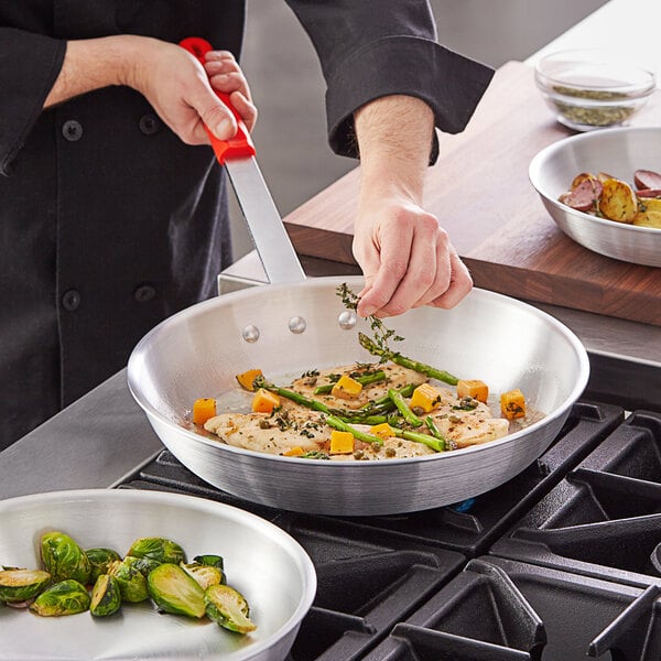 A person cooking brussels sprouts in a Choice Aluminum Fry Pan on a stove.