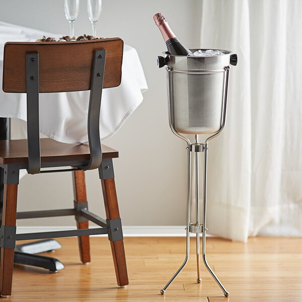 An American Metalcraft champagne bucket on a stand with a champagne bottle and glass.