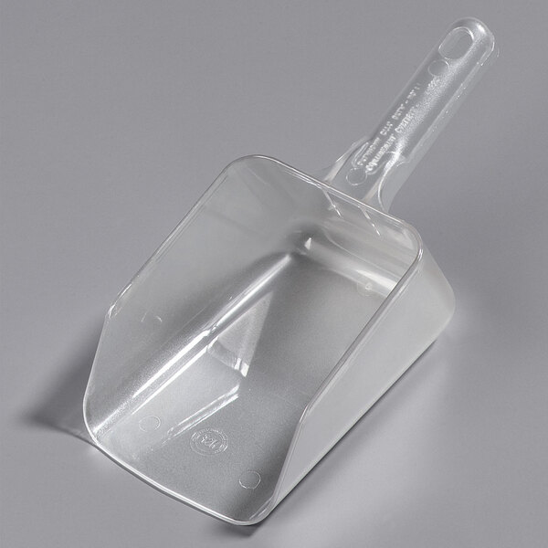 A Carlisle clear plastic utility scoop on a white surface.