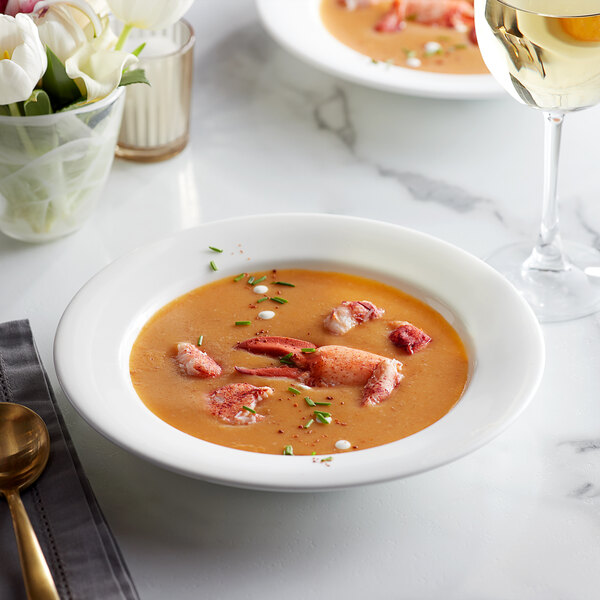 A bowl of soup with Boston Lobster Company claw and knuckle lobster meat and a glass of white wine.