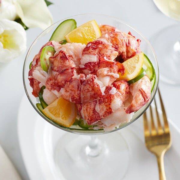 A glass dish of Boston Lobster Company lobster salad with cucumber and lemon slices.