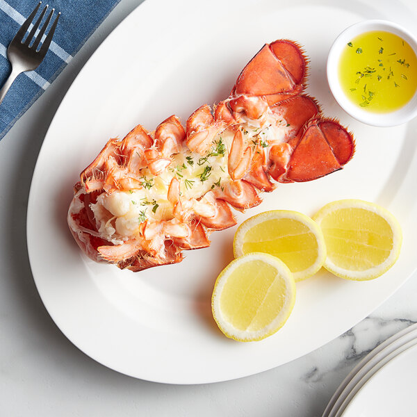 A Boston Lobster Company 7-8 oz. lobster tail on a plate with lemon slices and sauce.