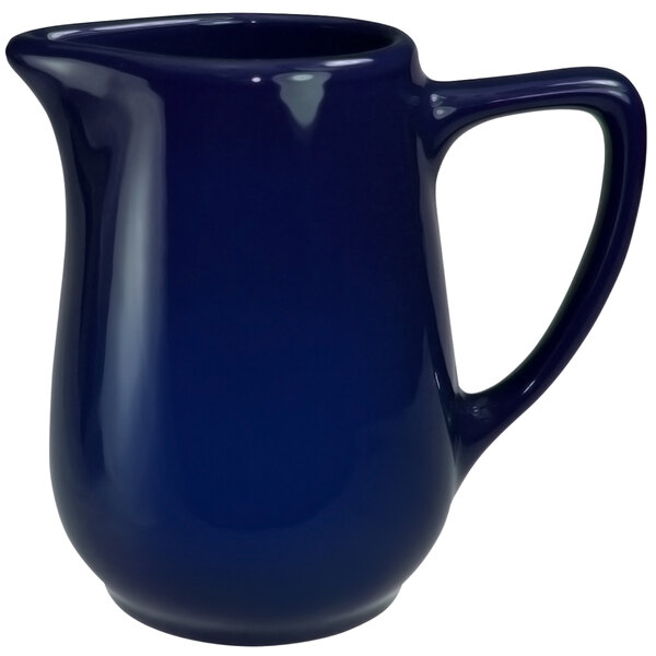 A blue International Tableware stoneware creamer with a handle.
