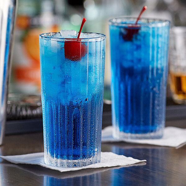 Two Duralex Manhattan highball glasses filled with blue liquid and cherries.