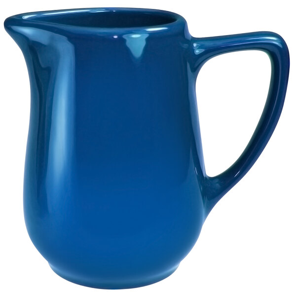 A light blue stoneware creamer with a handle.