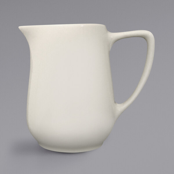 An International Tableware Roma ivory creamer with a handle.