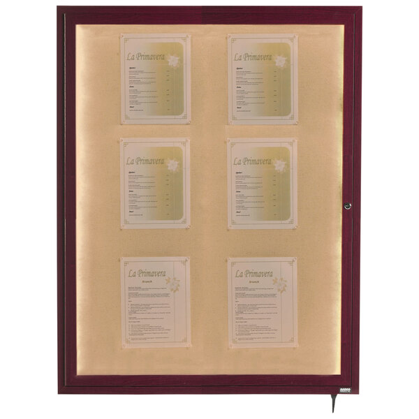 An Aarco cherry finish bulletin board cabinet with white papers on it.