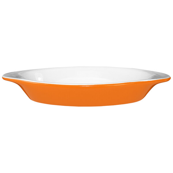An International Tableware orange and white oval rarebit dish with a white rim.