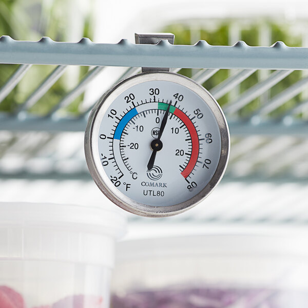 A Comark UTL80 refrigerator/freezer thermometer hanging on a rack.